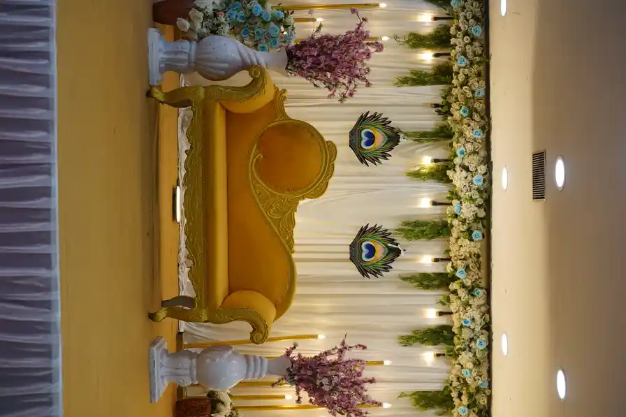 Close detail of the gold mandap backdrop, draped with florals and peacock motifs