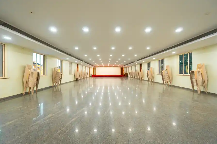 The bare hall with chairs stacked along the walls, showing its full length