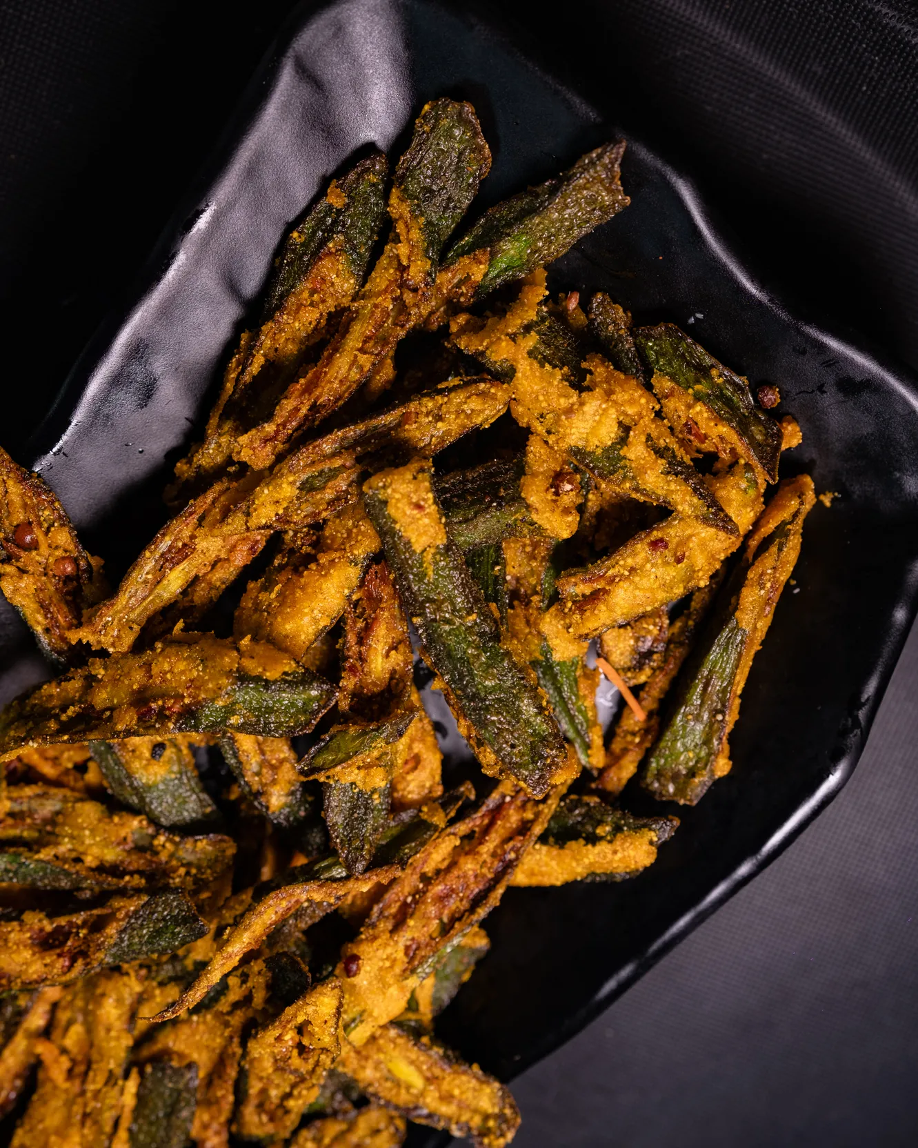 A close view of crisp fried okra strips with turmeric and chilli