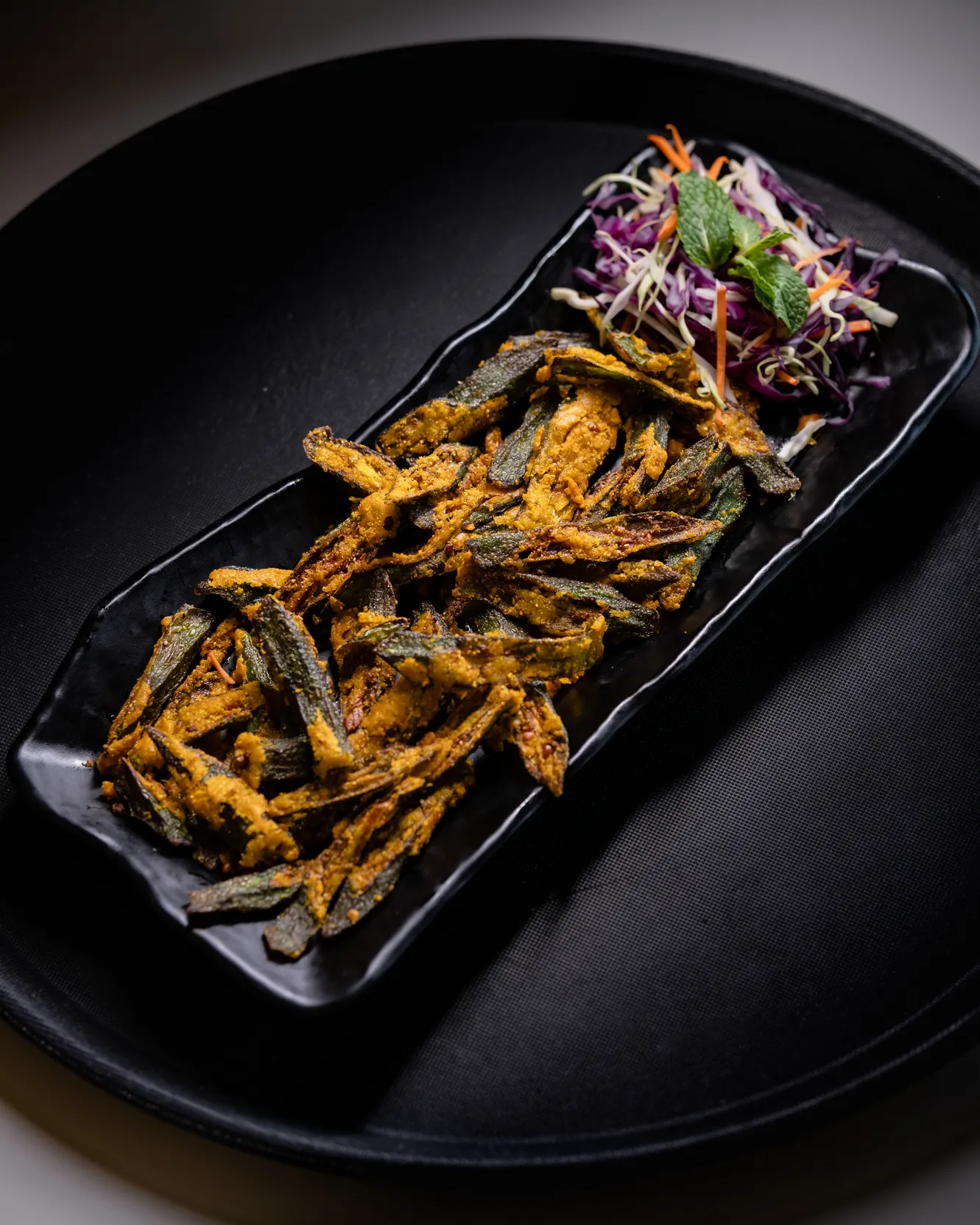 Crisp fried okra tossed with spices on a long black platter