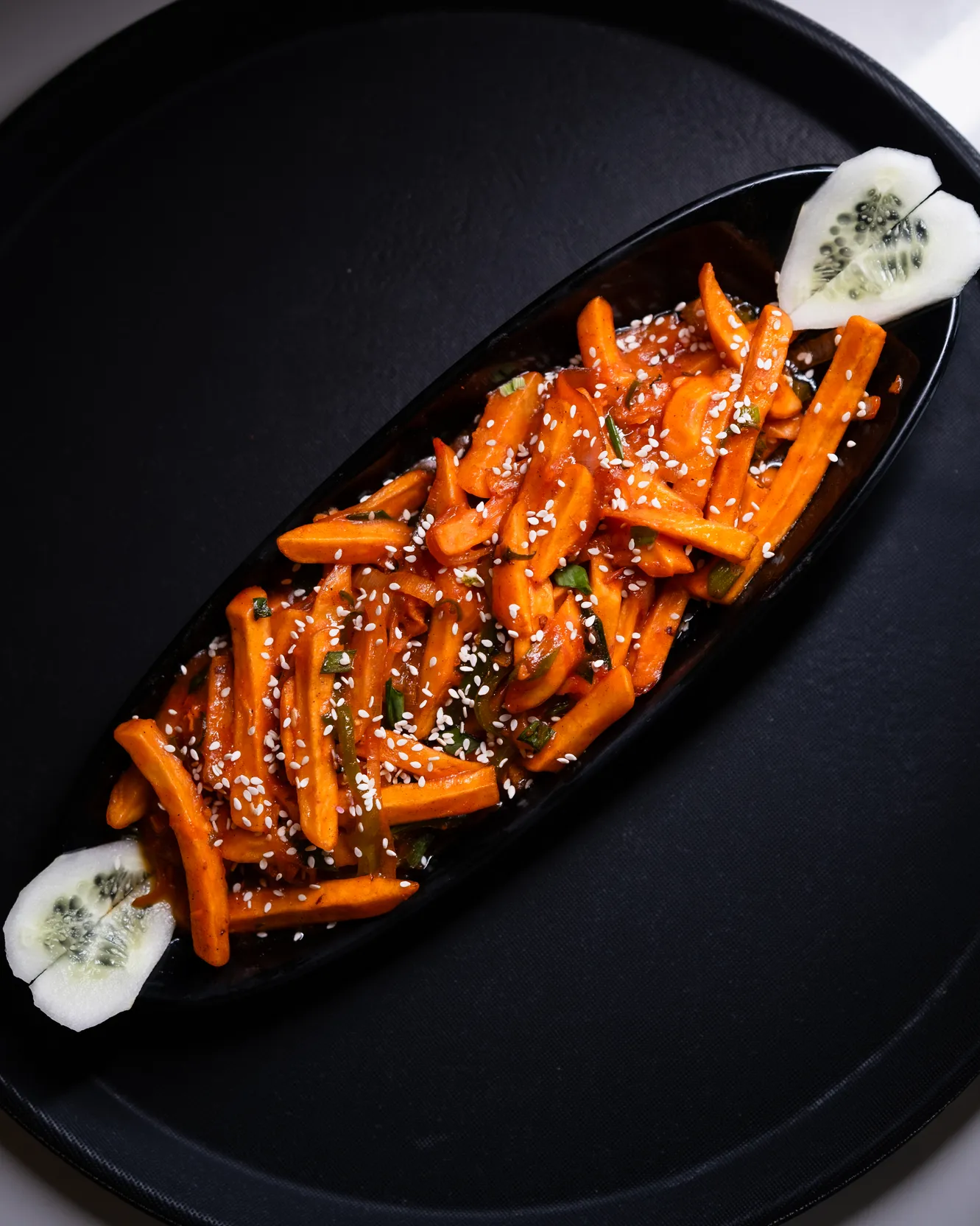 Honey chilli carrot sticks with sesame on a long black platter