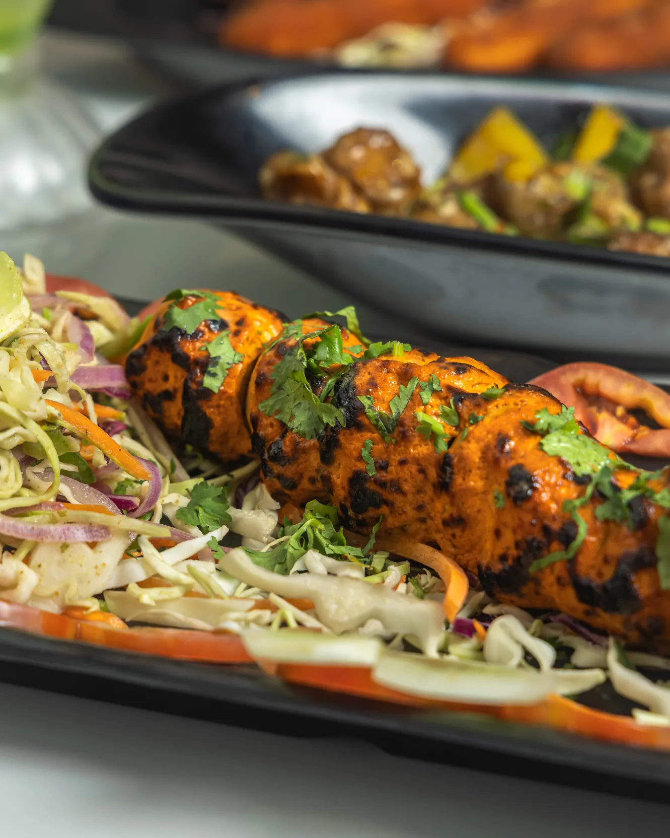 A tandoori paneer skewer resting on a bed of shredded salad