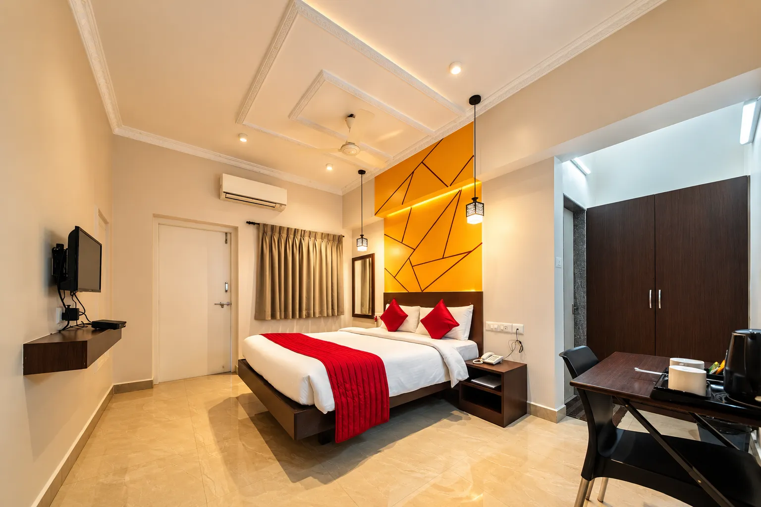 A Deluxe room with a queen bed, red runner, writing desk and wardrobe