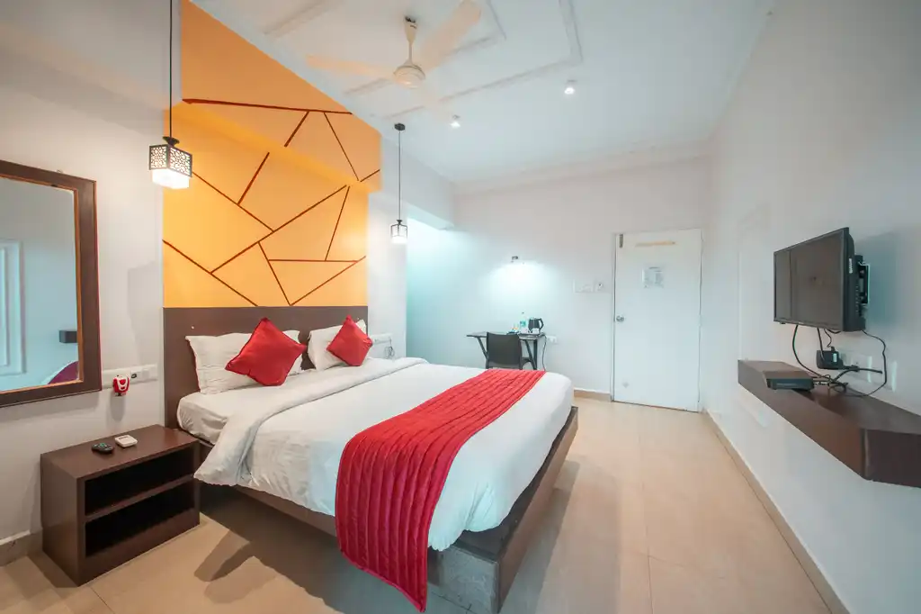 A Deluxe room showing the bed, wall-mounted television and mirror