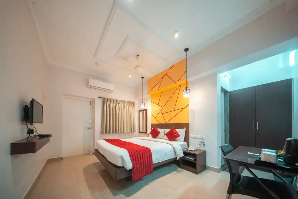 A Deluxe room with the bed, television, wardrobe and desk in view